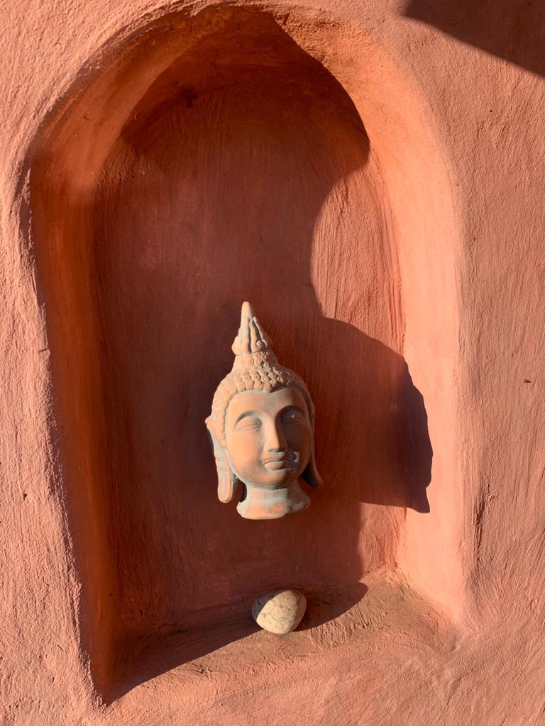 Buddha-Kopf in Niesche in terrakottafarbener Wand